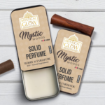 Mystic Wood Solid Perfume for Men in a sleek tin, styled with vetiver roots, cedarwood pieces, sandalwood bark, and amber resin on a white background.