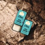 Woman smiling in sunlight with Citrus Bloom perfume in hand, expressing freshness and vitality.