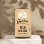 Golden Serenity solid perfume tin displayed aesthetically on a rustic wooden platform with soft ambient light.